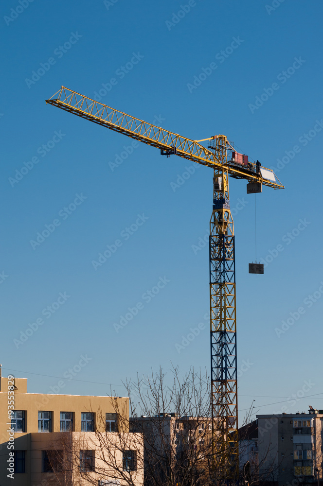 yellow crane lifting materials on building site, vertical view
