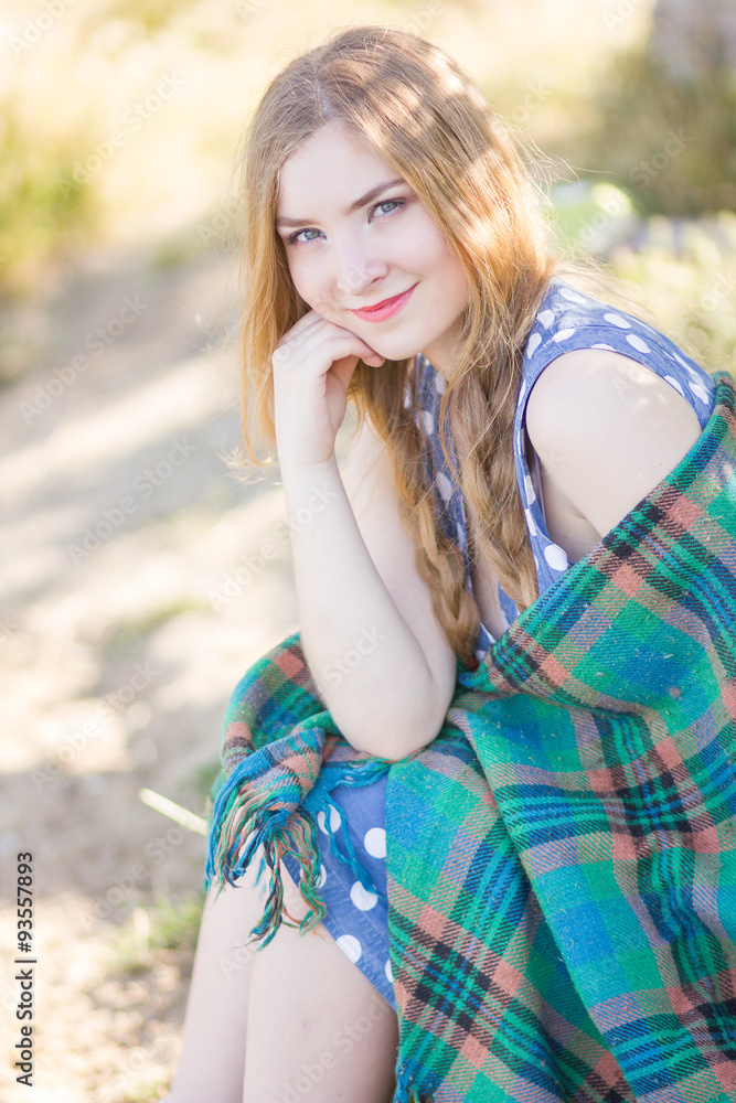 Naklejka premium Beautiful happy woman with long hair on the nature, covered blanket 