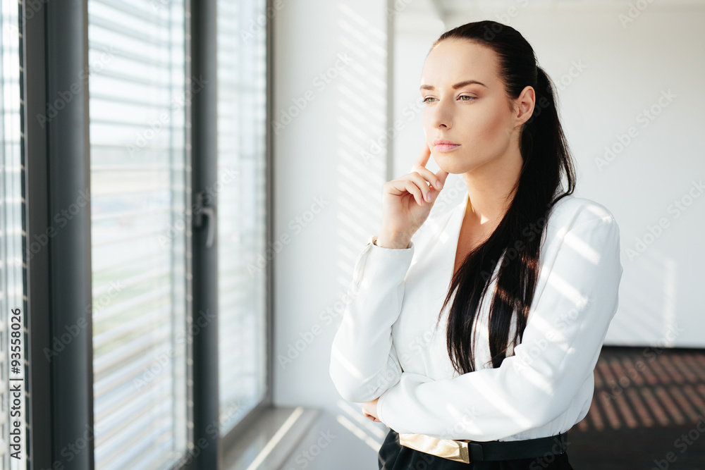 Woman executive standing by the window and looking through it Woman executive standing by the window and looking through it