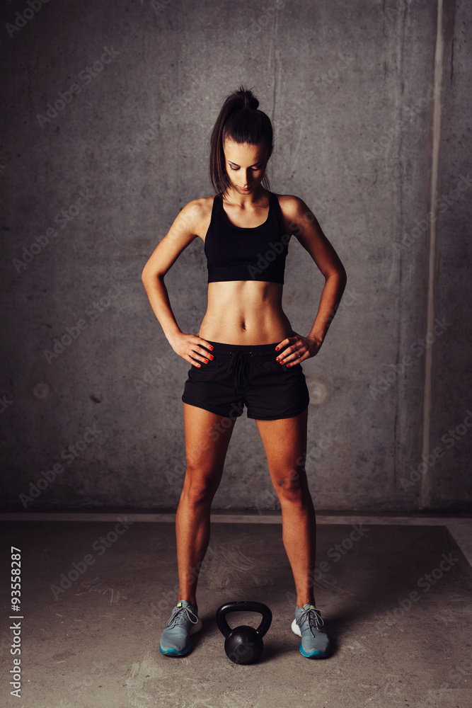 Sportswoman looking at a kettlebell Sportswoman looking at a kettlebell