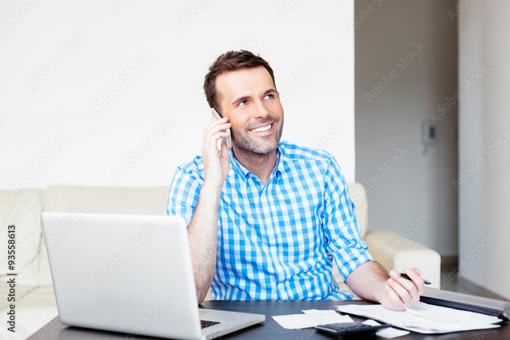Optimistic young man paying his bills online Optimistic young man paying his bills online