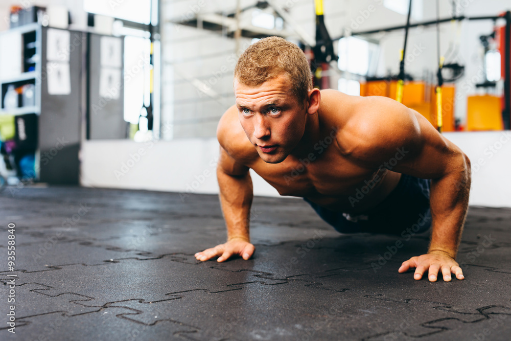 Obraz premium Young muscular athlete practicing suspension pushups