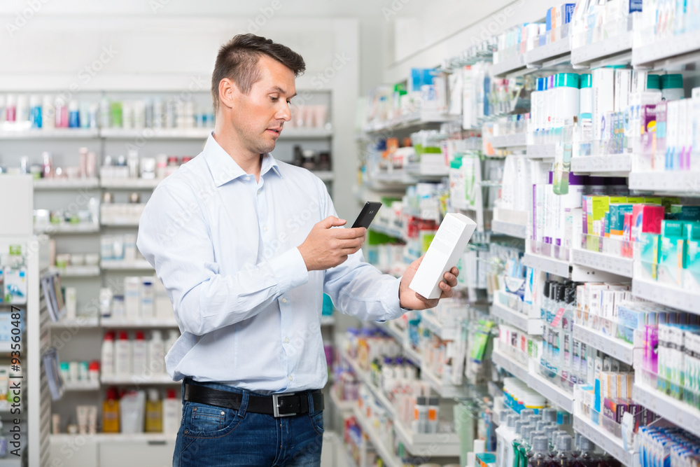 Male Customer Scanning Product Through Mobile Phone In Pharmacy Male Customer Scanning Product Through Mobile Phone In Pharmacy
