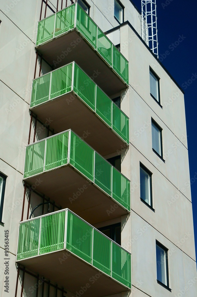 White modern residential building with green balconies White modern residential building with green balconies
