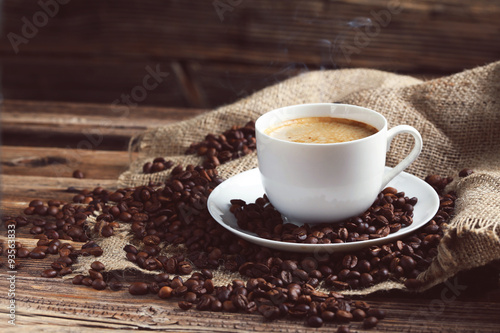 Cup of coffee with coffee beans on a brown wooden background