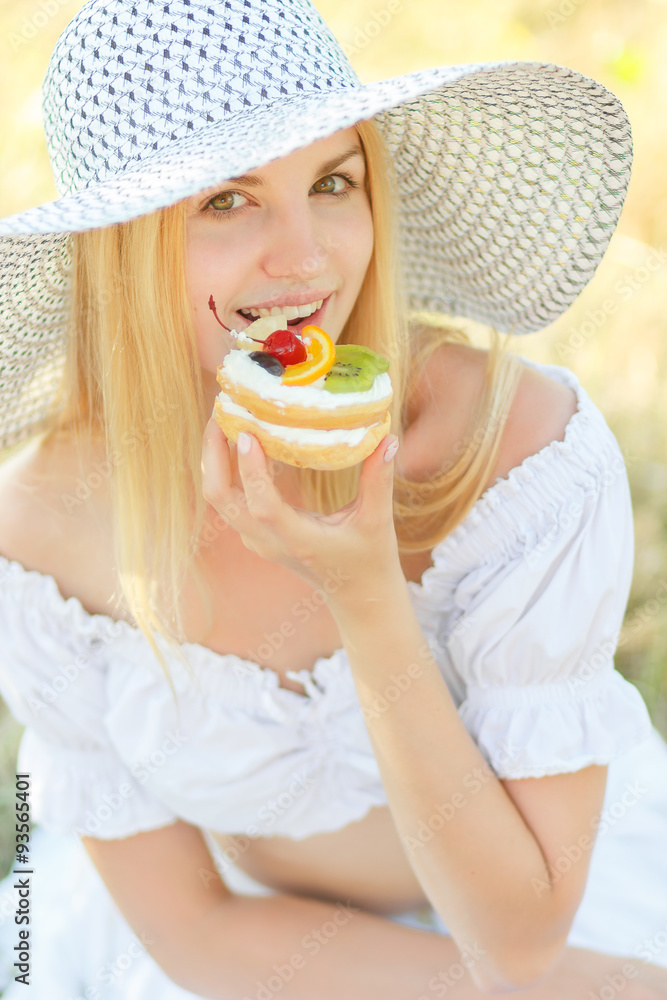 Young pretty blonde fashion girl sensual portrait posing outdoor in summer eating cake with fruits Young pretty blonde fashion girl sensual portrait posing outdoor in summer eating cake with fruits