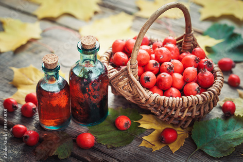 Tincture bottles of hawthorn berries, ripe thorn apples in baske photo