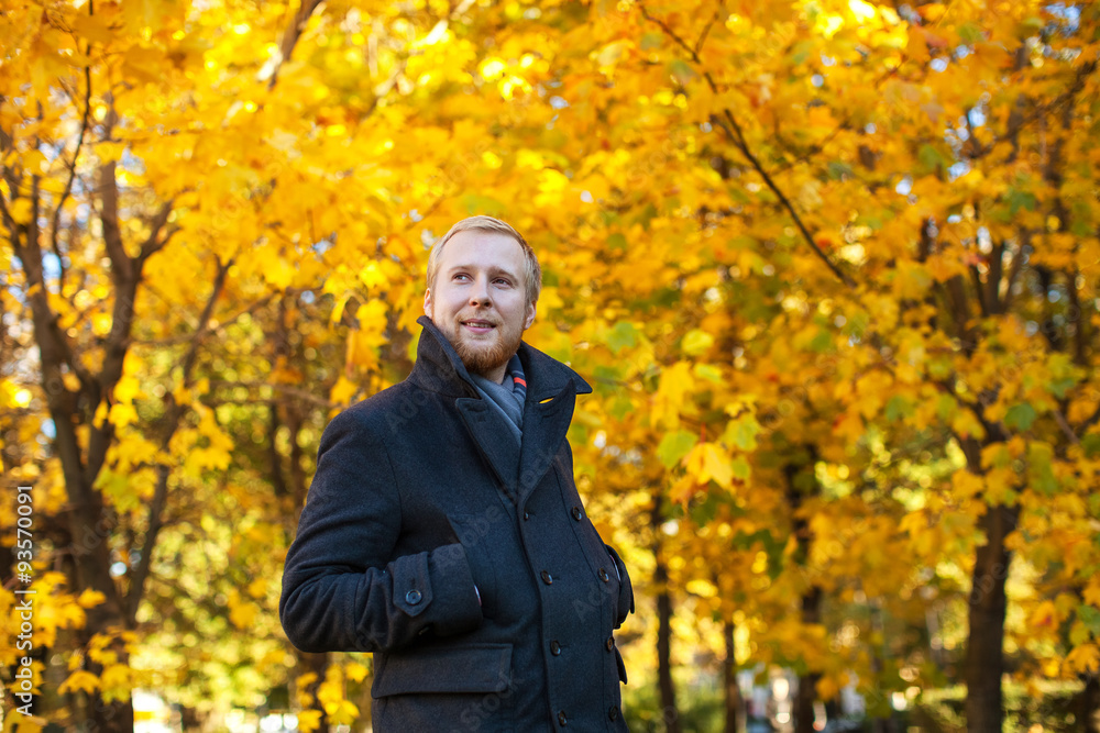 a man dressed in a dark coat and scarf in autumn park a man dressed in a dark coat and scarf in autumn park