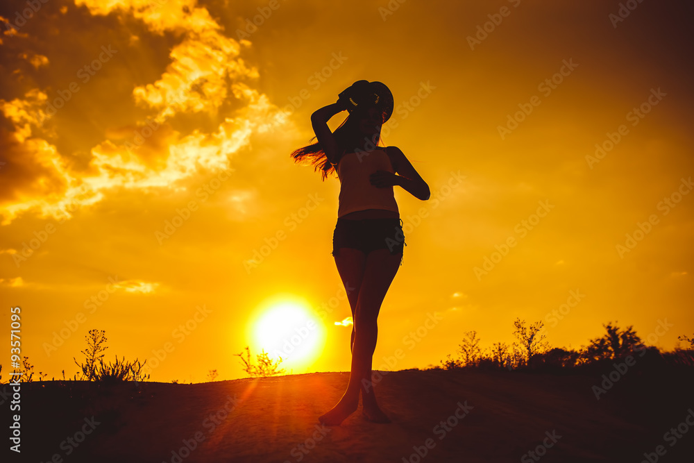 silhouette of a young girl in a shirt and shorts holds over his 