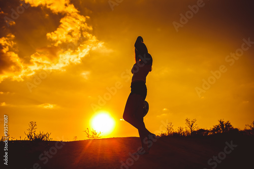 silhouette of a young girl in a shirt and shorts holds over his 