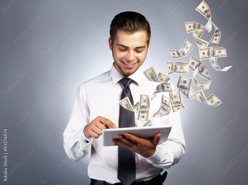 Businessman holding tablet with money fly out of it Businessman holding tablet with money fly out of it