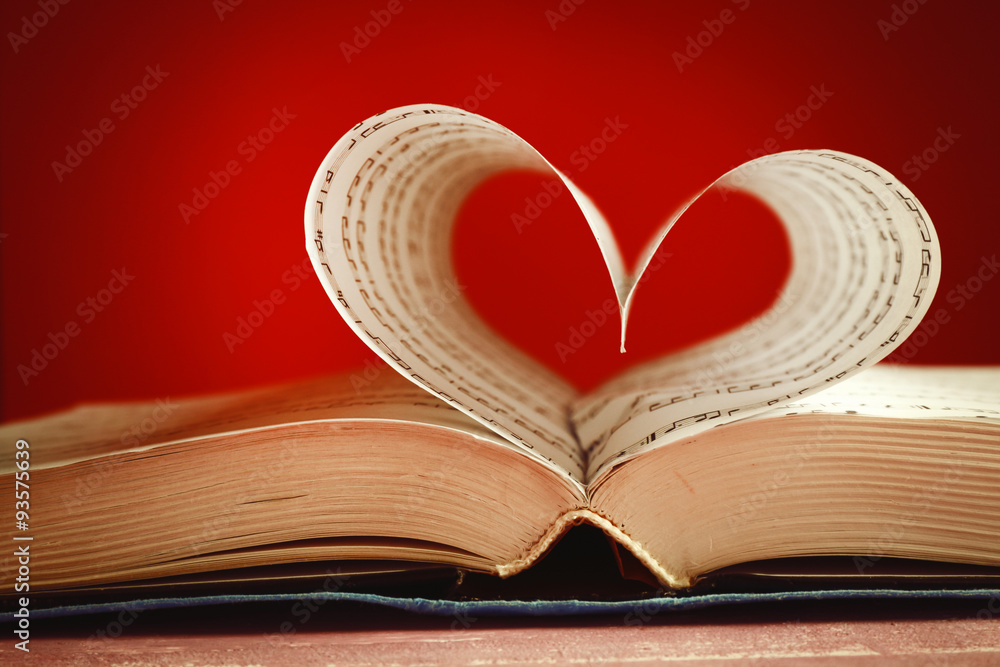 Book pages curved into heart shape on pink background Book pages curved into heart shape on pink background