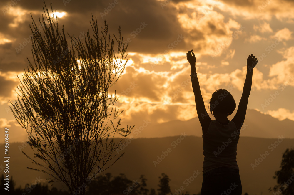 Teenage girl posing with sunset behind clouds in background