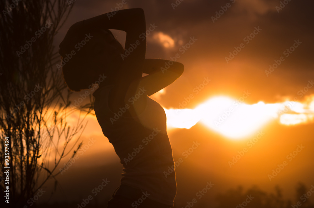 Teenage girl posing with sunset behind clouds in background