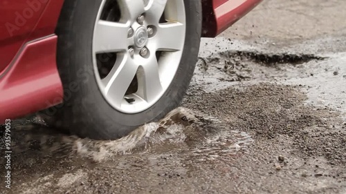 Car Hits Two Pot Holes. slow motion of a car driving through two potholes filled with water. splashing everywhere. 
