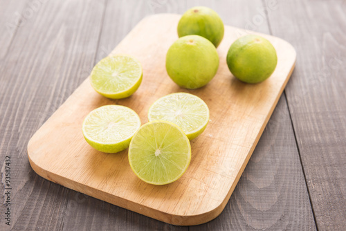 Fresh limes on cutting board on wooden table