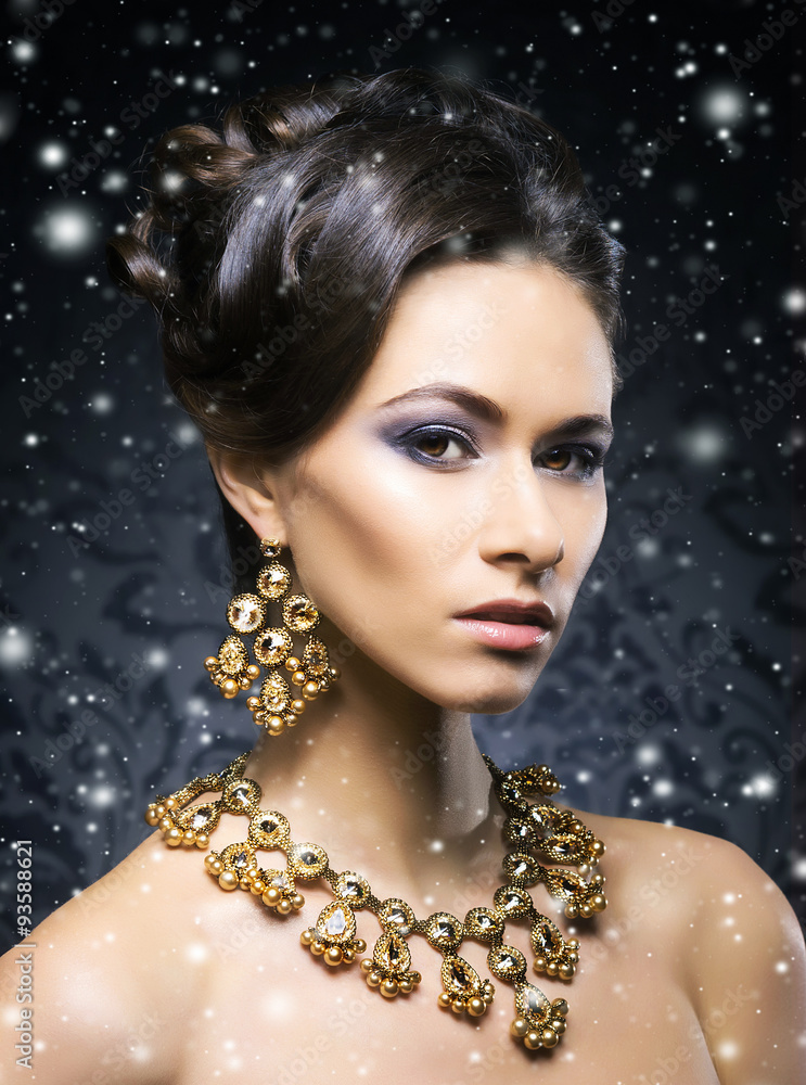Young, beautiful and rich woman in jewels of gold and stones ove