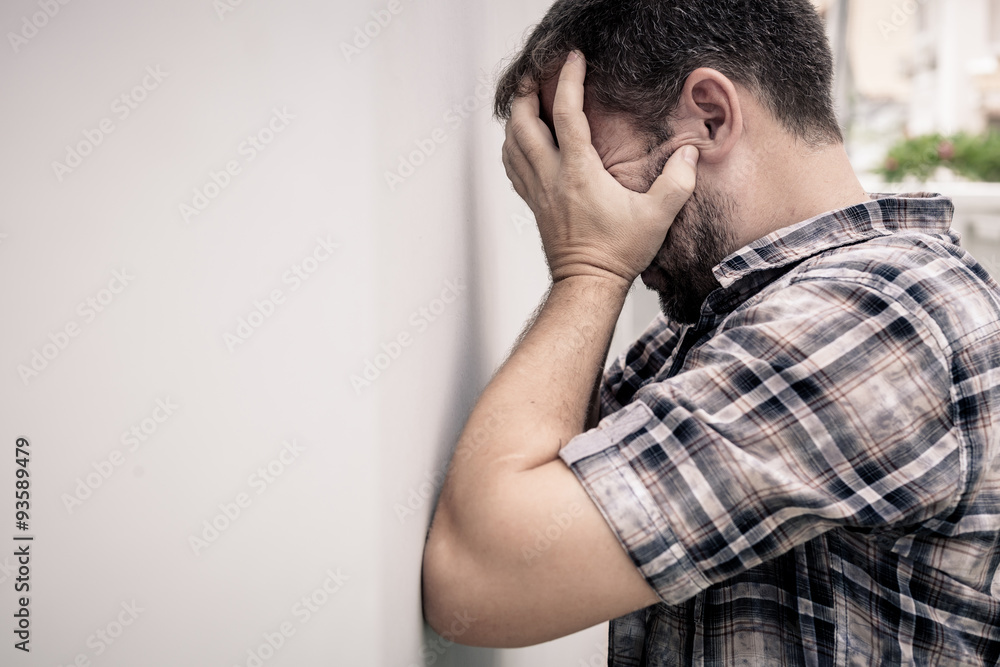 portrait one sad man standing near a wall and covers his face portrait one sad man standing near a wall and covers his face