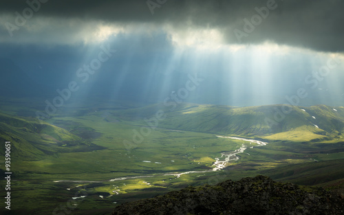 Sun rays shining through the dark clouds and shining on a river in Iceland.
