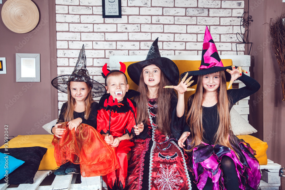 Boys and girls, dressed up in Halloween costumes, show emotions of witches and vampires. Halloween party with group children.