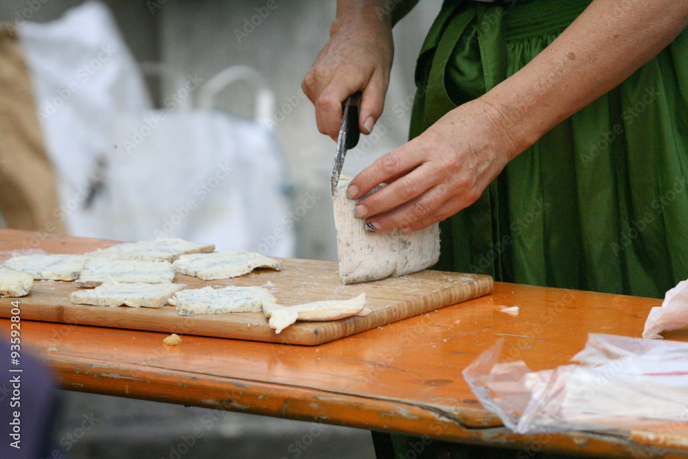 Frau im Dirndl schneidet Käse in Scheiben Frau im Dirndl schneidet Käse in Scheiben