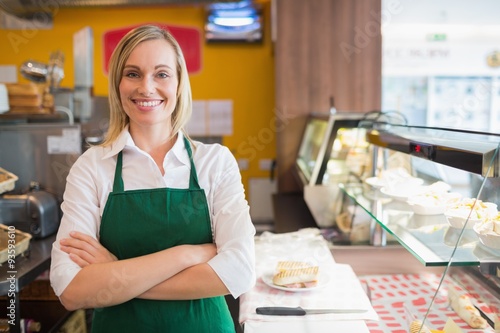 Foto Confident female shop owner standing by display cabinet