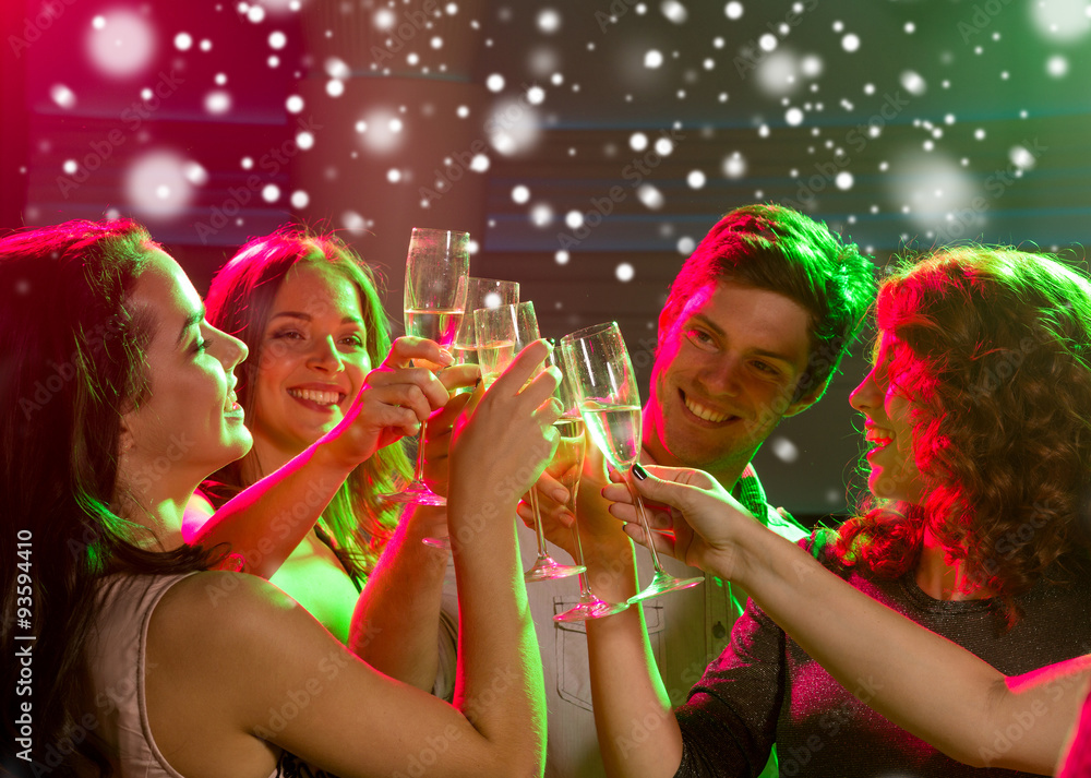 Obraz premium smiling friends with glasses of champagne in club