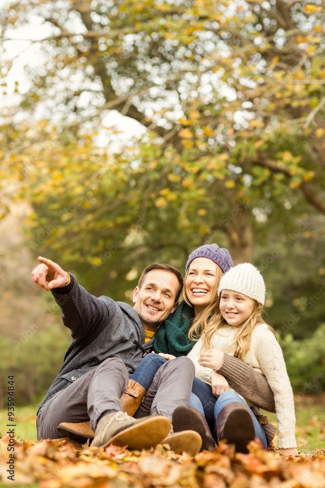 Fototapeta premium Smiling young family sitting in leaves