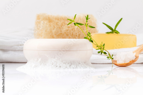 Herbal spa soap bar on white bath towel with thyme,rosemary and