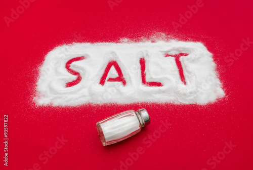 Salt shaker and text out of white powder on a red baclkground suggesting toxic ingredients if used in an excessive manner photo