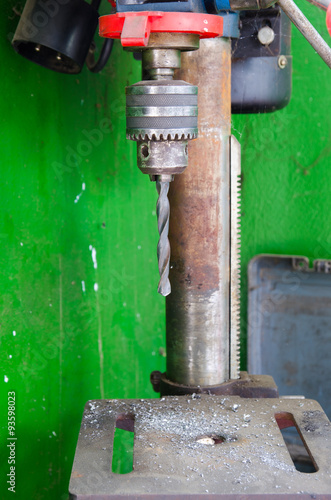 Fototapeta Heavy duty industrial drill with metal pieces everywhere a dirty green background
