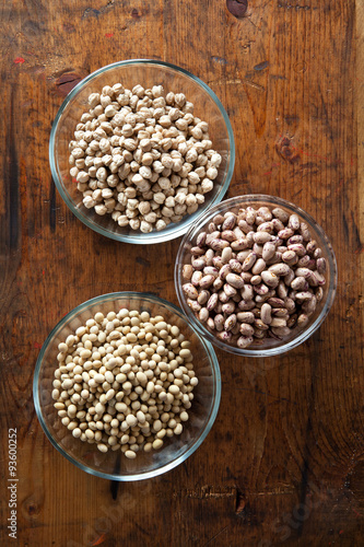 Bowls of various legumes (soybeans, chickpeas, beans) on wooden
