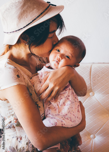 Obraz na plátně Asian woman hold tight and kiss her daughter's head