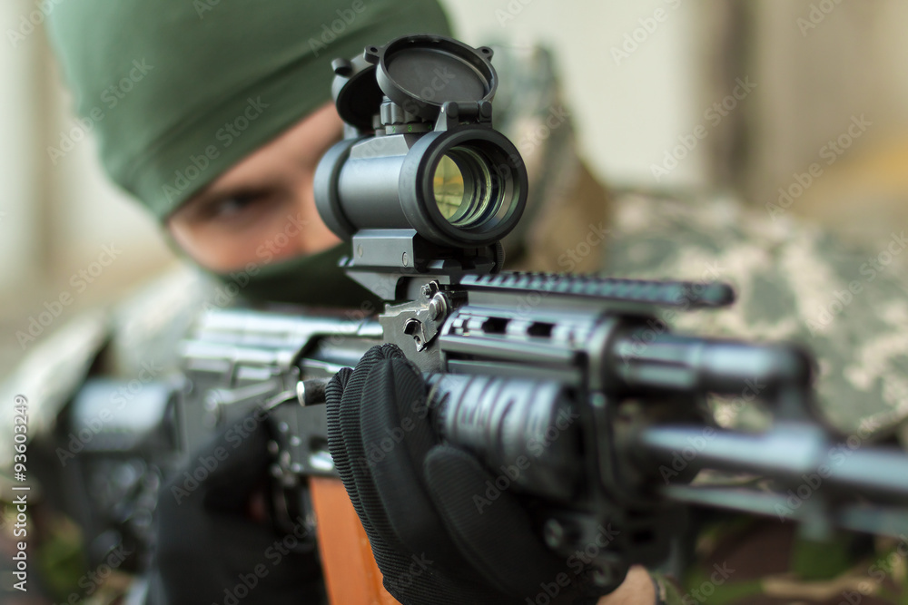 man aiming with an AK-47 with reflex sight