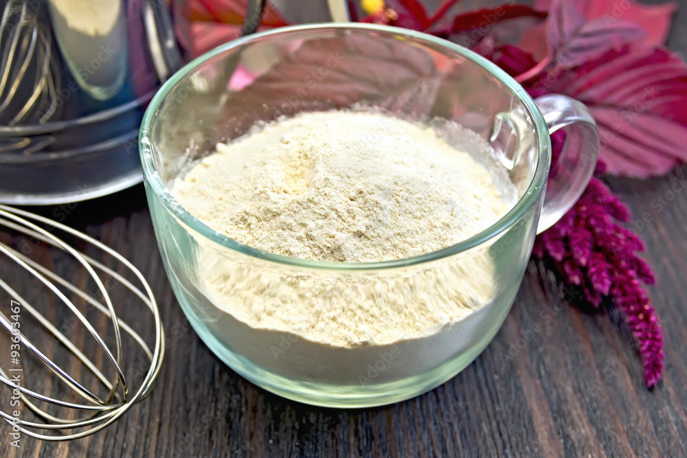 Flour amaranth in glass cup with sieve on board