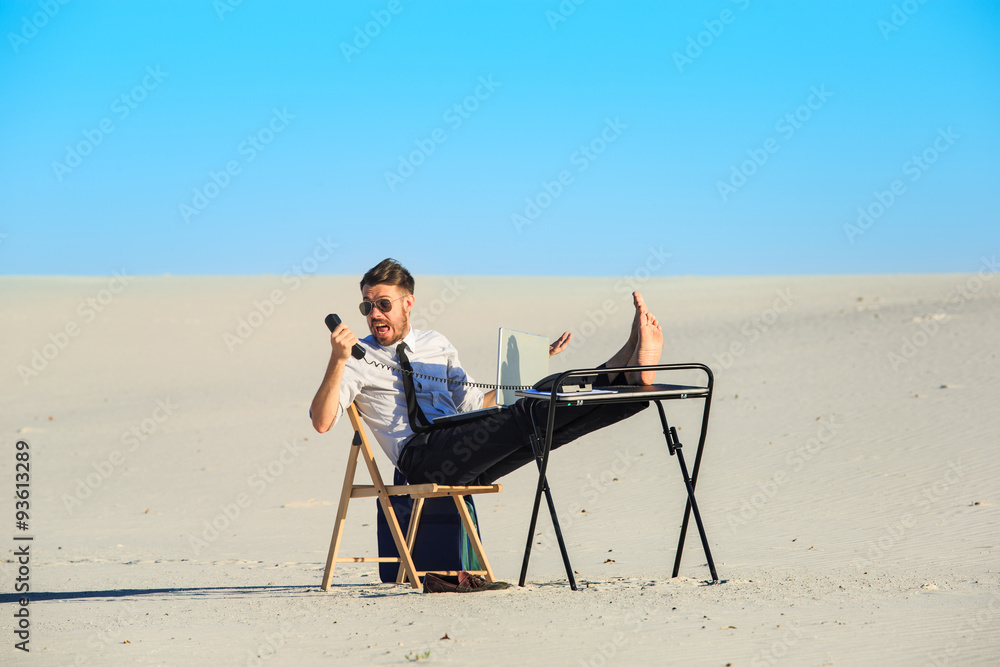 Businessman using  laptop in a desert