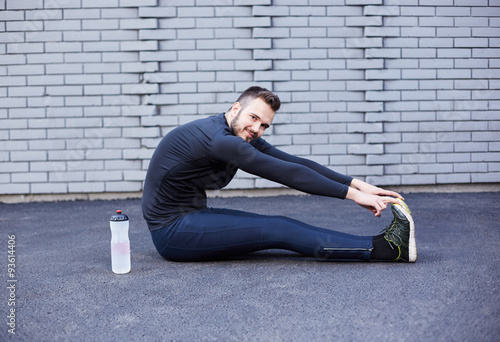 Sport man with beard stretching against concrete wall © Myvisuals