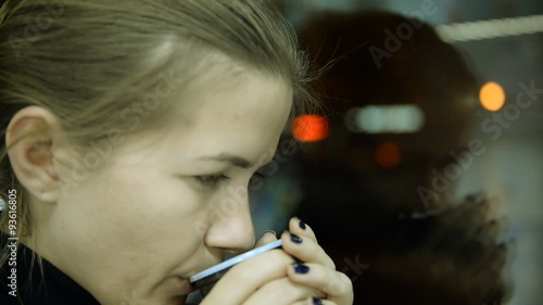 City, showcase glass. Depressed woman drinking tea by the window in home 