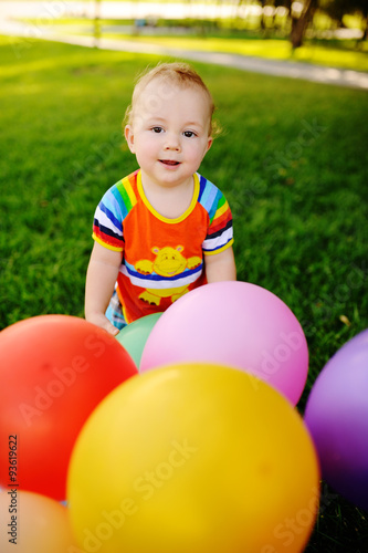 baby boy with colored balloons on a background of grass