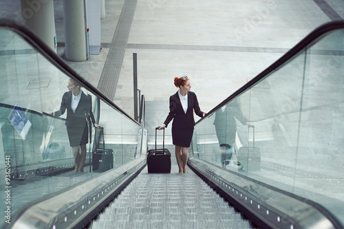 Businesswoman on escalator with hand luggage