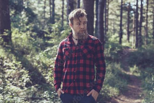 Man with beard in pine tree forest.