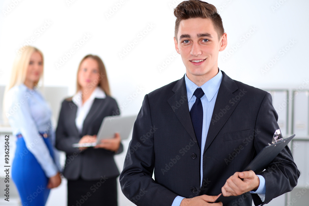 Cheerful business man in office with colleagues in the background, sturt-up team Cheerful business man in office with colleagues in the background, sturt-up team
