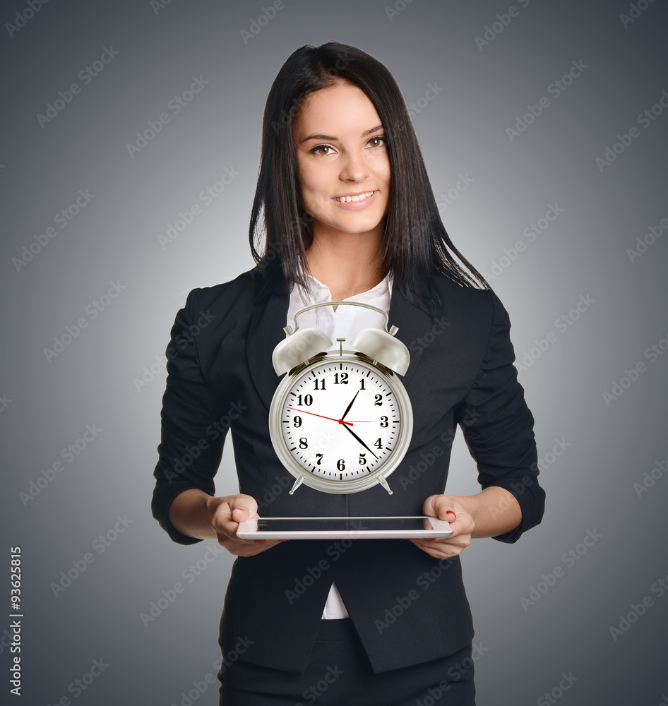 Business woman showing a metal alarm clock in front of him Business woman showing a metal alarm clock in front of him