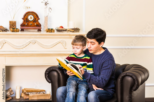 Father and little son reading book on Christmas evening