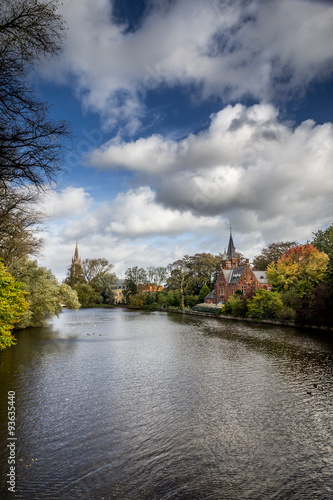 Romantic lake Minnewater in Autumn with its famous house with towers and Church Of Our Lady in Bruges, Belgium. © ajcabeza