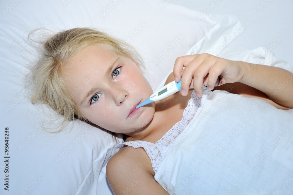 Cute sick child measures the temperature in bed Cute sick child measures the temperature in bed
