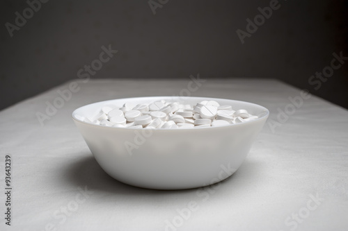 plate filled with medical pills drugs is on the table with a white cloth on a dark background