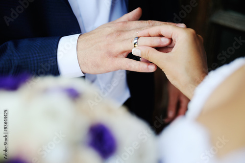 bride groom wears a wedding ring on his finger