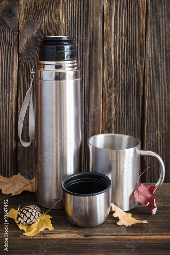Silver opened thermos flask and metal travel cup