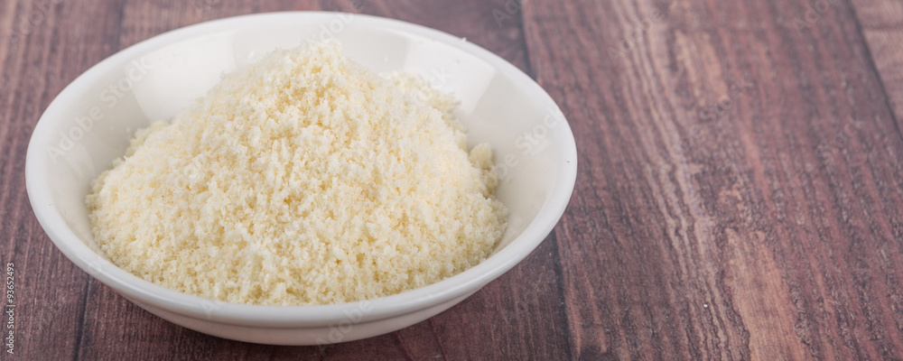 Grated cheese in white bowl over wooden background Grated cheese in white bowl over wooden background